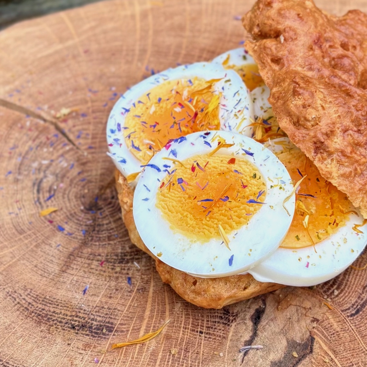 Serviervorschlag Ostersalz mit Blüten auf einem mit Ei belegtem Brötchen