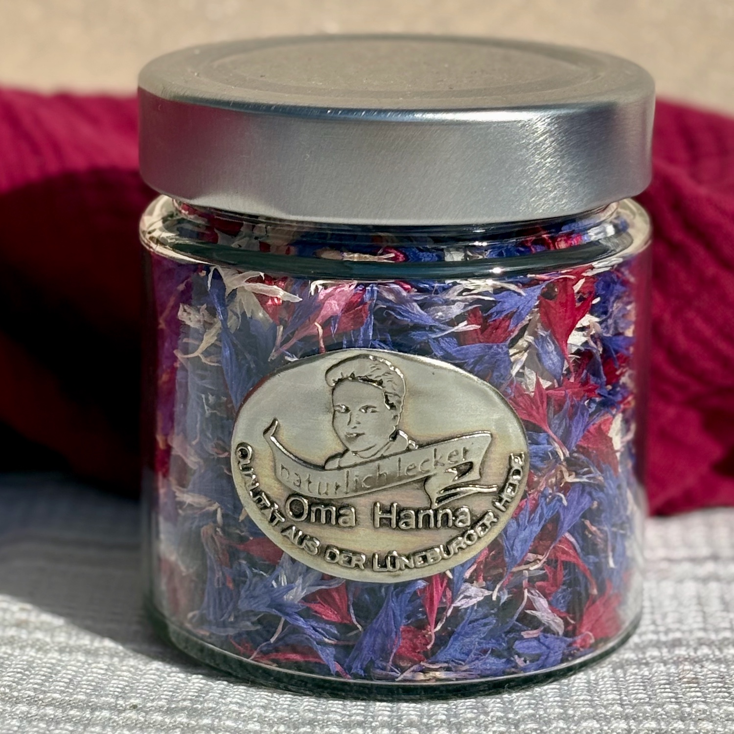 Glas mit essbaren Kornblumenblüten in bunt mit rosa, blau, rot und weißen Kornblumenblüten one Kelche als Blütenstreusel