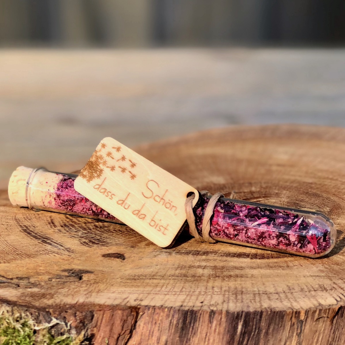 Gastgeschenk Stullengewürz im Reagenzglas mit Anhänger Pusteblume Schön dass du da bist auf einer Holzscheibe liegend